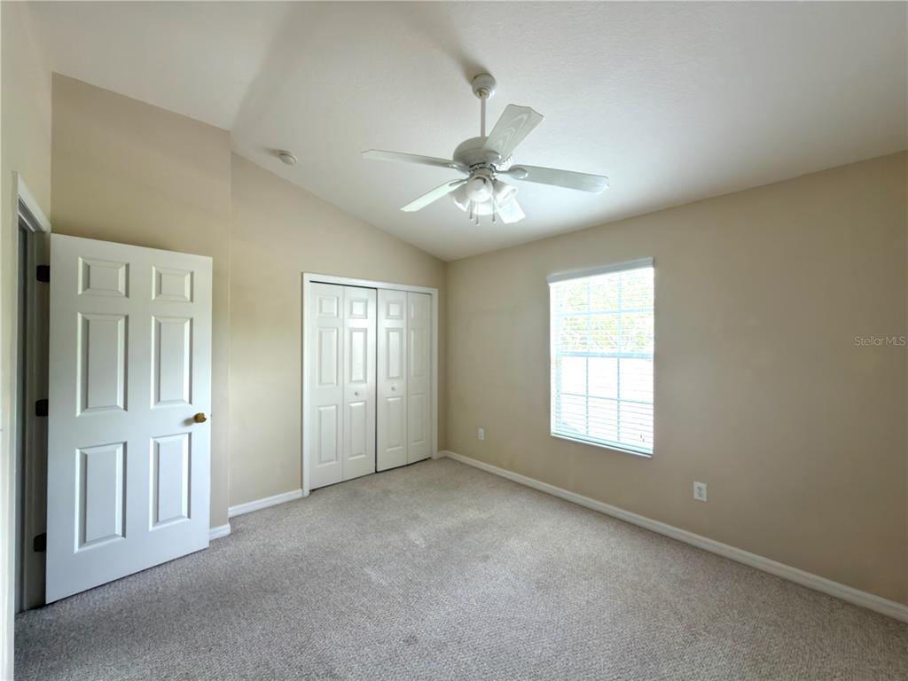 An empty bedroom features beige walls, carpeted flooring, a ceiling fan, and a closet — 2437 EARLSWOOD COURT, BRANDON, FL