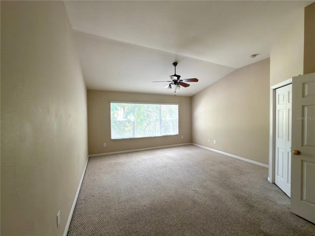 An empty bedroom with beige carpet, a vaulted ceiling, a ceiling fan, and a window — 2437 EARLSWOOD COURT, BRANDON, FL
