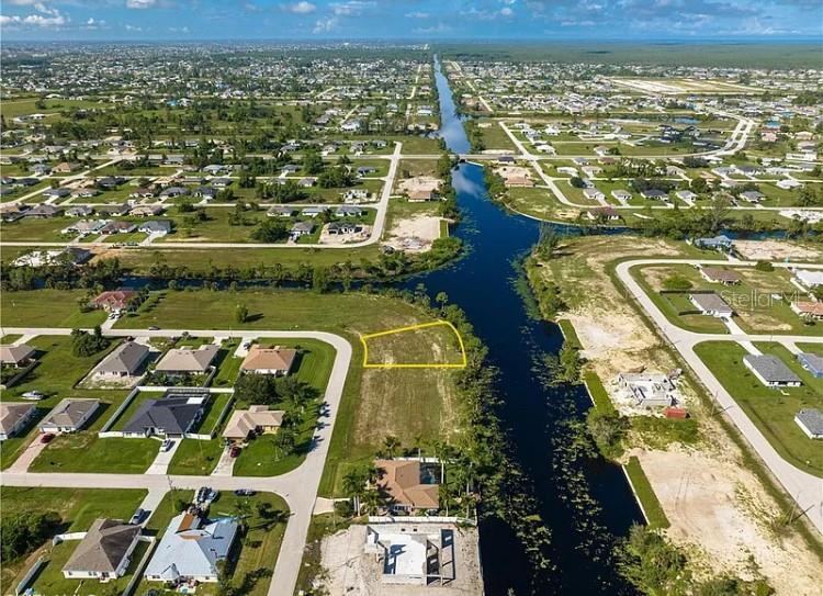 This aerial map shows a vacant residential lot highlighted in yellow along a canal — 2117 NE 43RD LANE, CAPE CORAL, FL