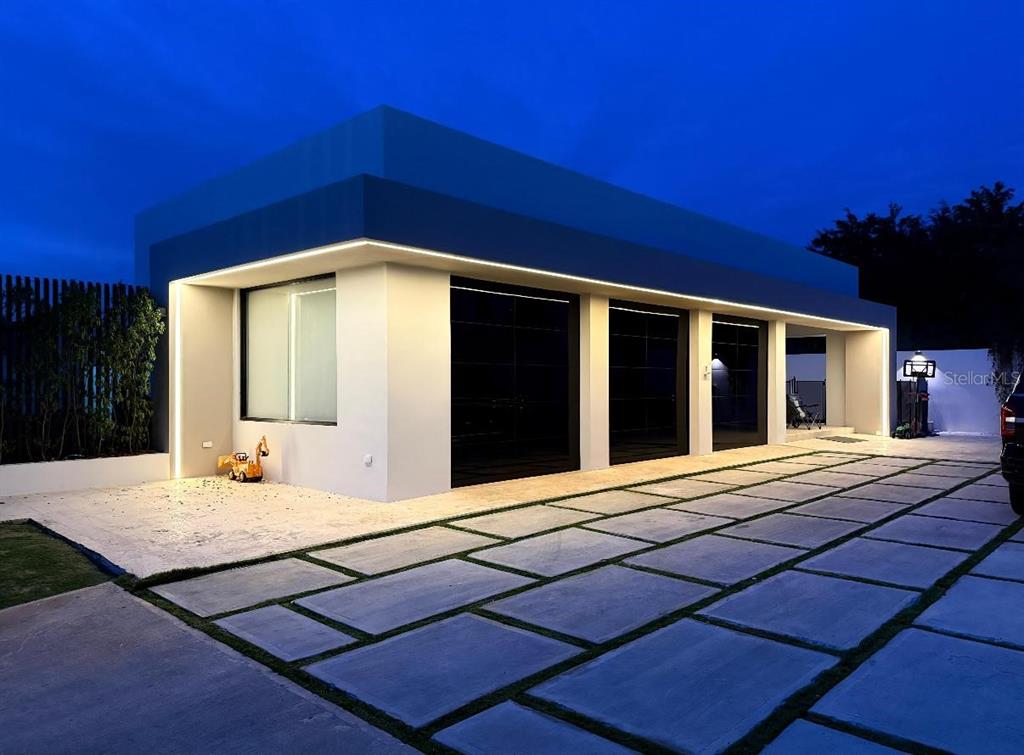 A modern house exterior at dusk features a three-car garage and a paved driveway — Bo Hato Arriba 492, ARECIBO, PR