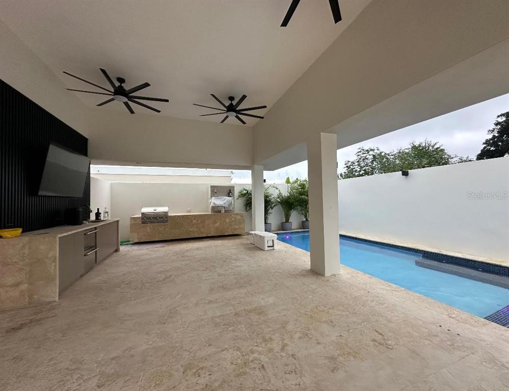 A covered outdoor patio features a stone kitchen counter, a swimming pool, and ceiling fans — Bo Hato Arriba 492, ARECIBO, PR
