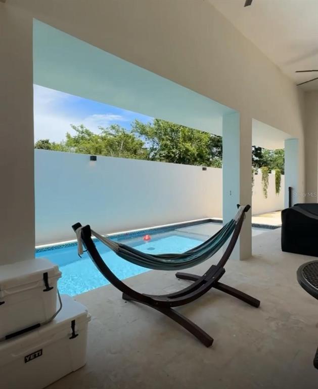 A covered patio features a hammock stand overlooking a swimming pool and a white wall — Bo Hato Arriba 492, ARECIBO, PR