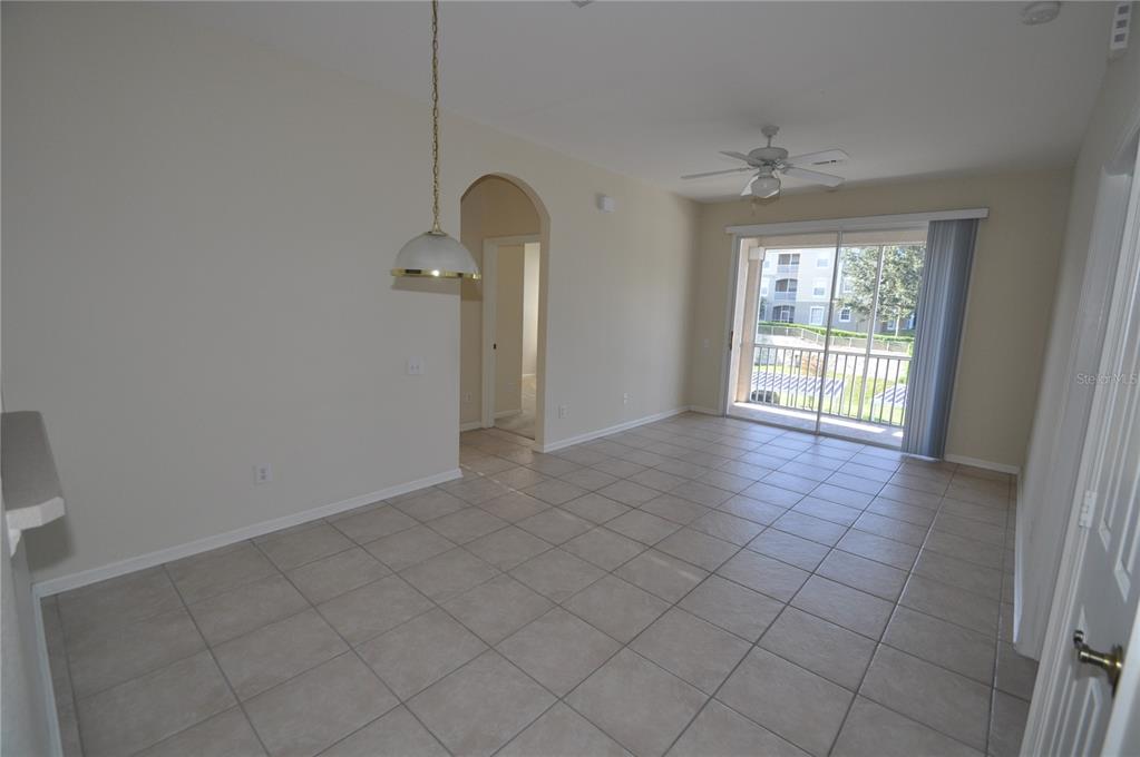 A galley kitchen features white cabinets, white appliances, beige countertops, and light-colored tile flooring — 588 BRANTLEY TERRACE WAY UNIT 305, ALTAMONTE SPRINGS, FL