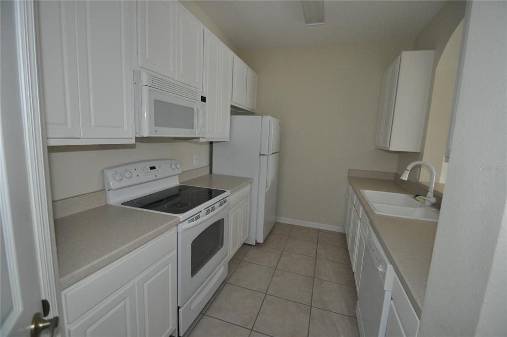 A kitchen with white cabinets, light countertops, tile flooring, and an arched entryway — 588 BRANTLEY TERRACE WAY UNIT 305, ALTAMONTE SPRINGS, FL