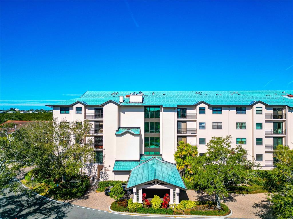 A multi-story apartment building with a teal metal roof and a covered entrance — 5408 EAGLES POINT CIRCLE UNIT 302, SARASOTA, FL
