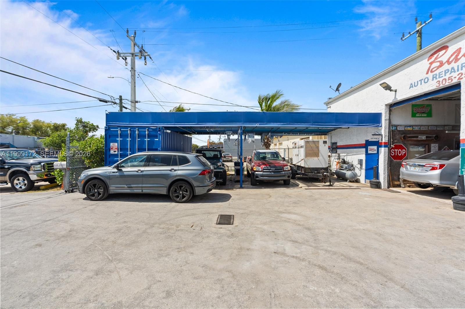 An exterior view of an auto repair shop with a blue canopy and parked vehicles — 10501 SW 185th Ter, Cutler Bay FL 33157, CUTLER BAY, FL