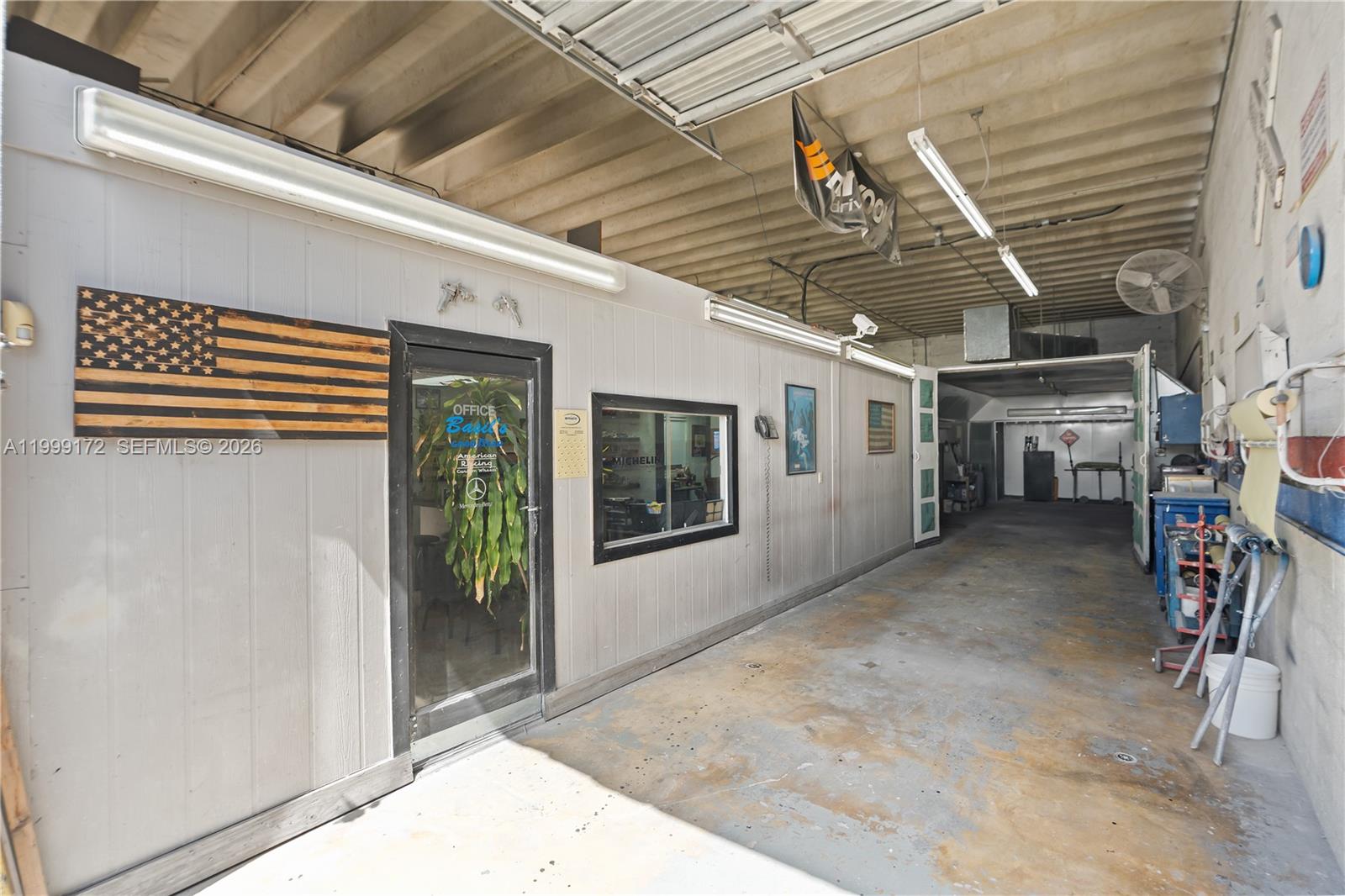 This industrial workshop features a small office enclosure with a wooden flag wall decoration — 10501 SW 185th Ter, Cutler Bay FL 33157, CUTLER BAY, FL