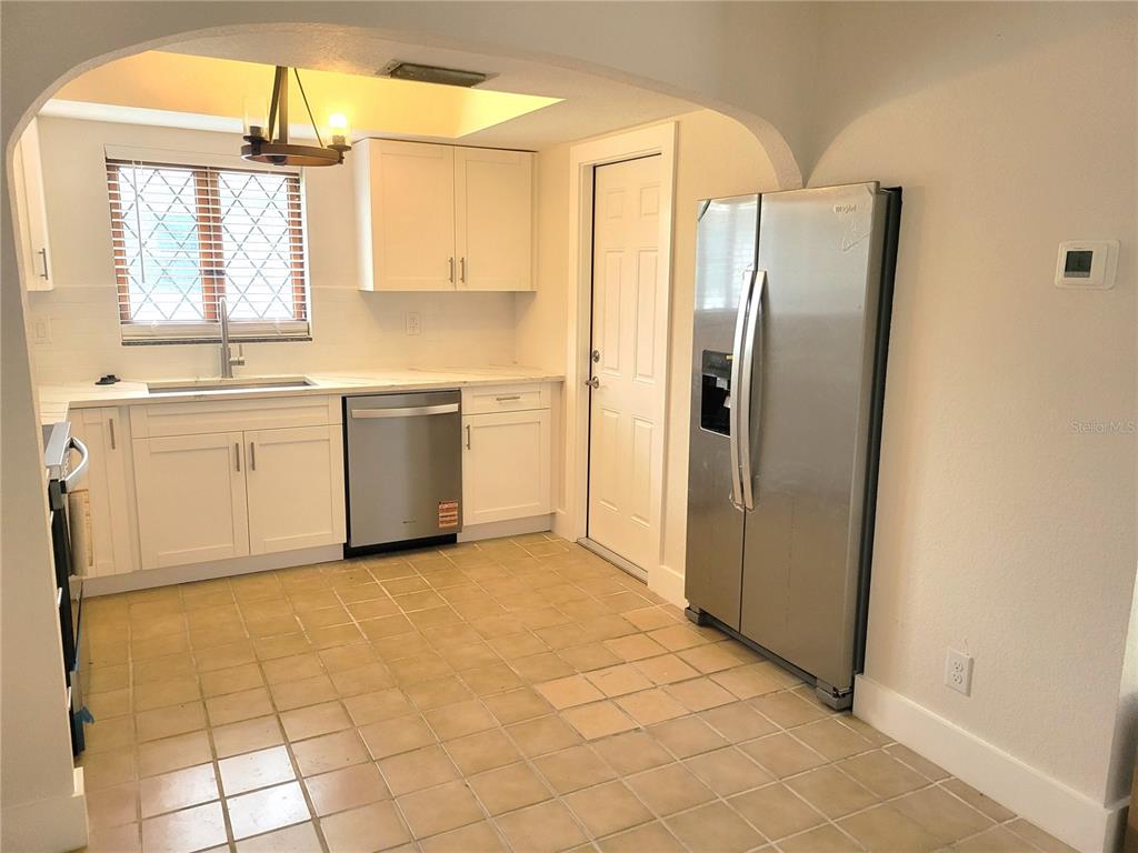 A kitchen features white cabinets, stainless steel appliances, a tile floor, and a window — 1835 MARYLAND AVENUE NE, ST PETERSBURG, FL