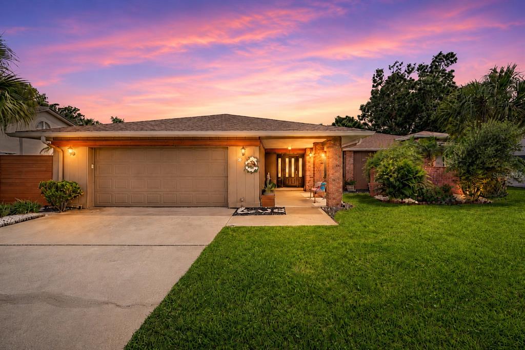 A single-story house with a tan garage, brick accents, and a front porch at sunset — 450 CYPRESS CREEK CIRCLE, OLDSMAR, FL