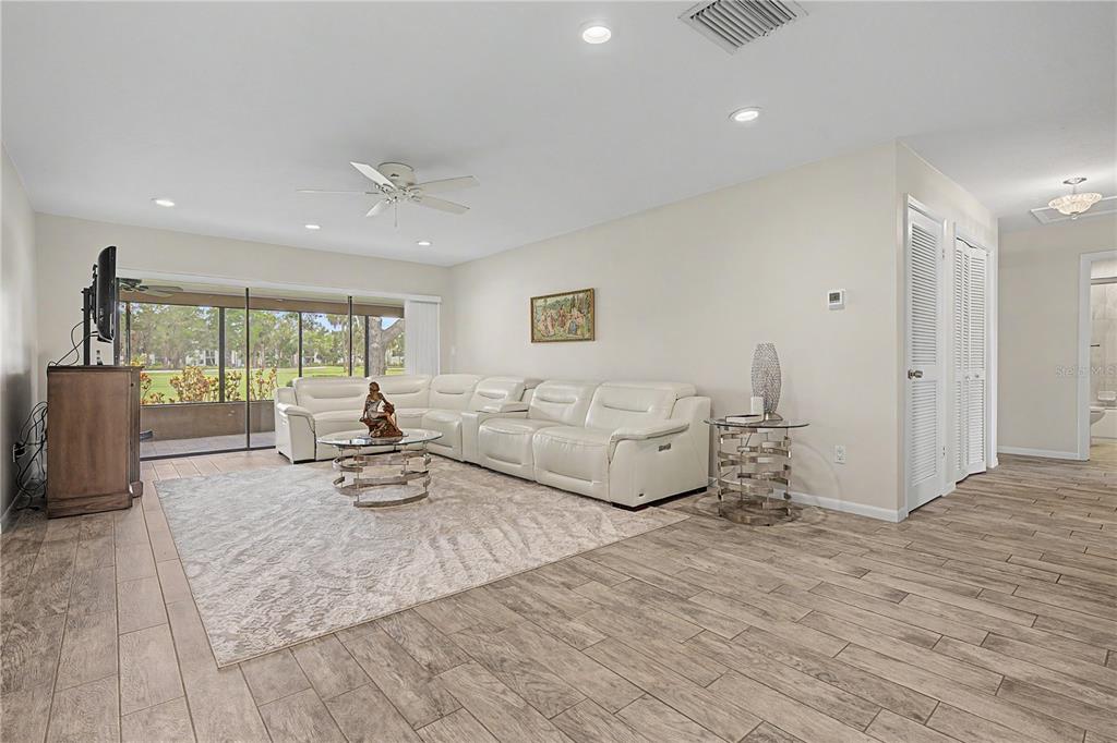 A living room features a white sectional sofa, a glass coffee table, and wood-look tile flooring — 450 CYPRESS CREEK CIRCLE, OLDSMAR, FL