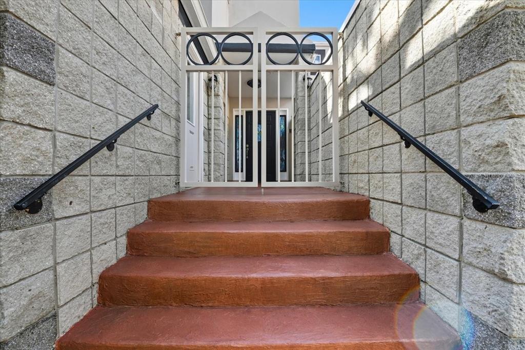A set of red concrete stairs leads up to a gated entryway with stone walls — 2713 CHAMBRAY LANE, TAMPA, FL
