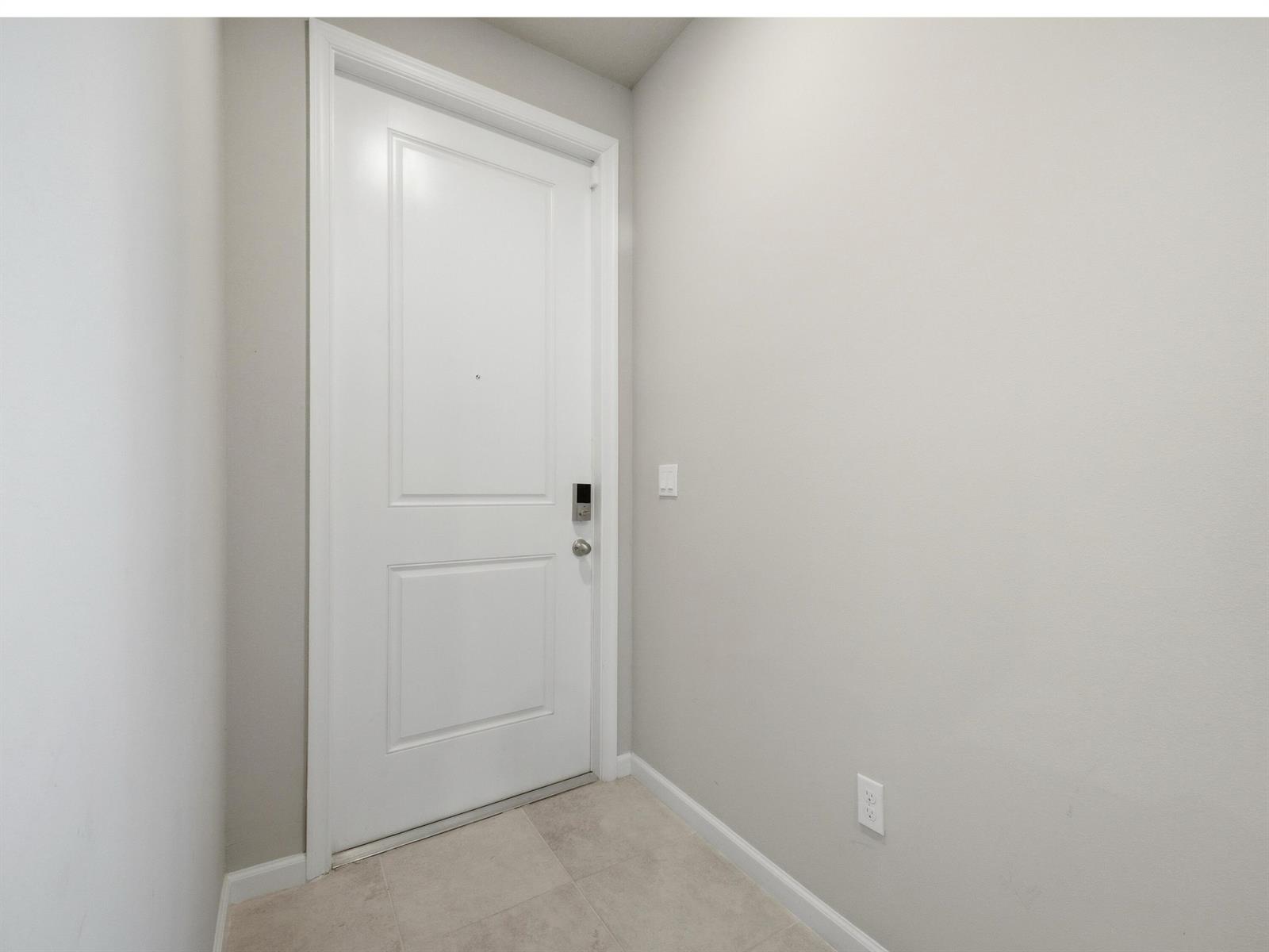 A white interior door with a smart lock stands in a room with light-colored walls — 5720 Mentmore Drive, West Palm Beach FL 33407, WEST PALM BEACH, FL