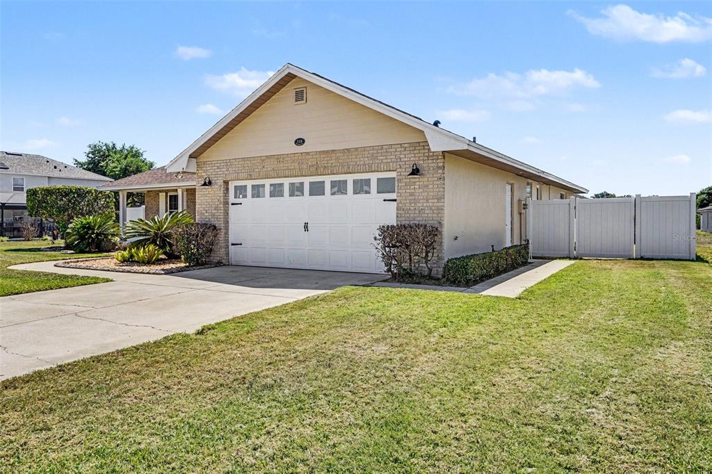 A single-story house with a beige brick facade, a two-car garage, and a white fence — 113 SHADDOCK DRIVE, AUBURNDALE, FL