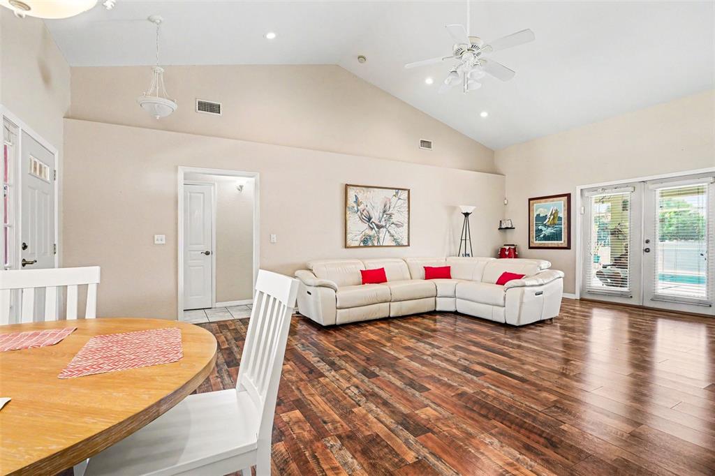 A living room with vaulted ceilings, wood flooring, and a white sectional sofa — 113 SHADDOCK DRIVE, AUBURNDALE, FL
