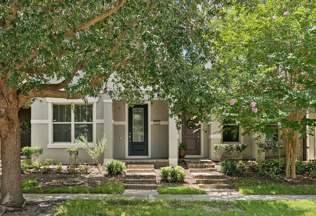 A two-story townhouse exterior with two front doors, brick steps, and mature trees in front — 7260 DUXBURY LN, WINTER GARDEN, FL