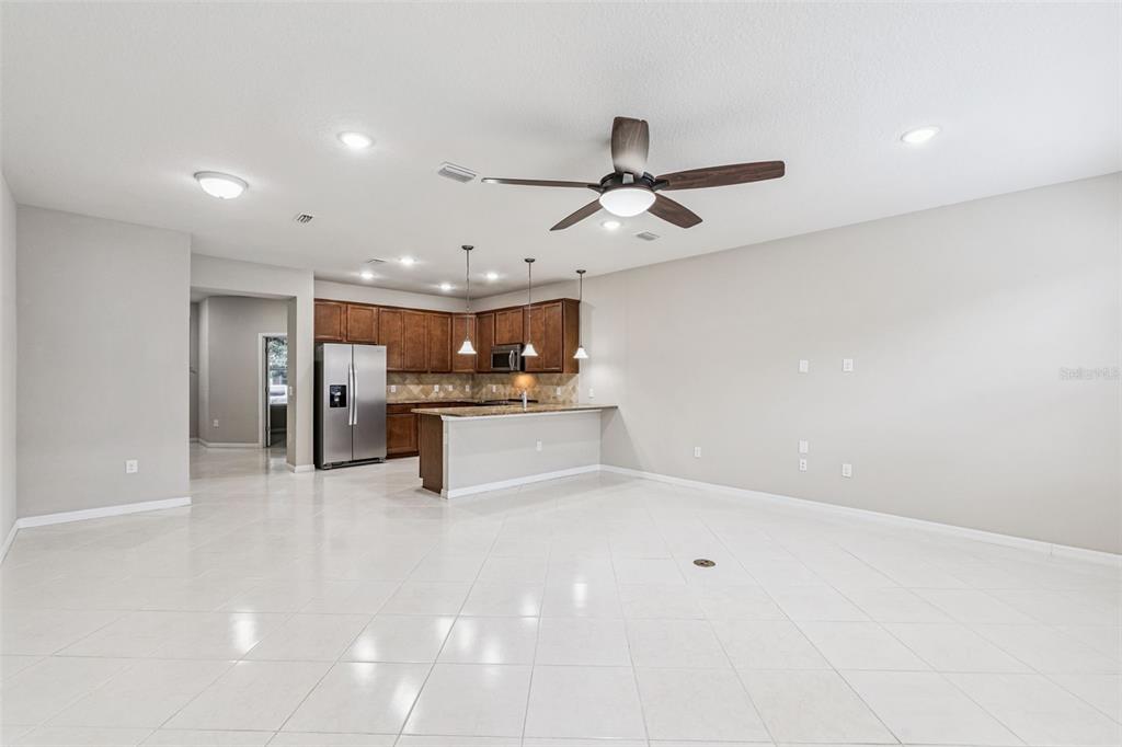 A spacious open-concept kitchen and living area with tile floors and a ceiling fan — 7260 DUXBURY LN, WINTER GARDEN, FL