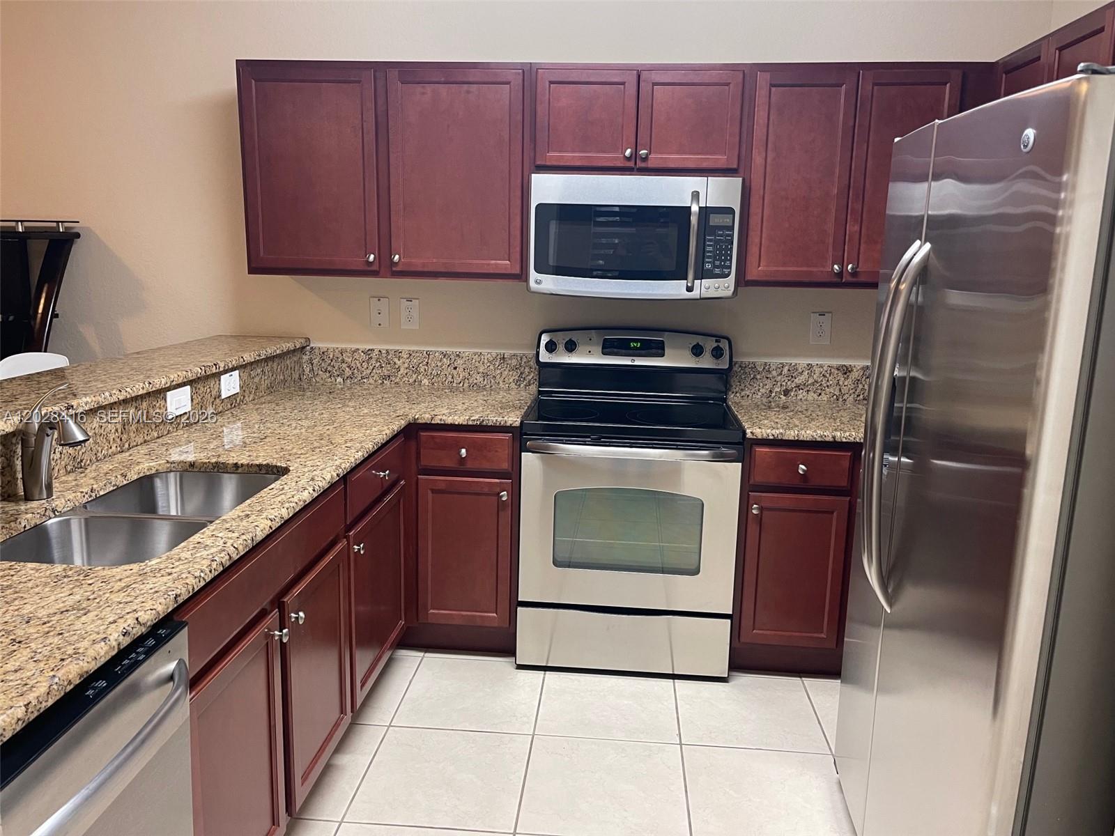 A kitchen features dark wood cabinets, granite countertops, and stainless steel appliances — 11601 NW 89th St # 225, Doral FL 33178, DORAL, FL
