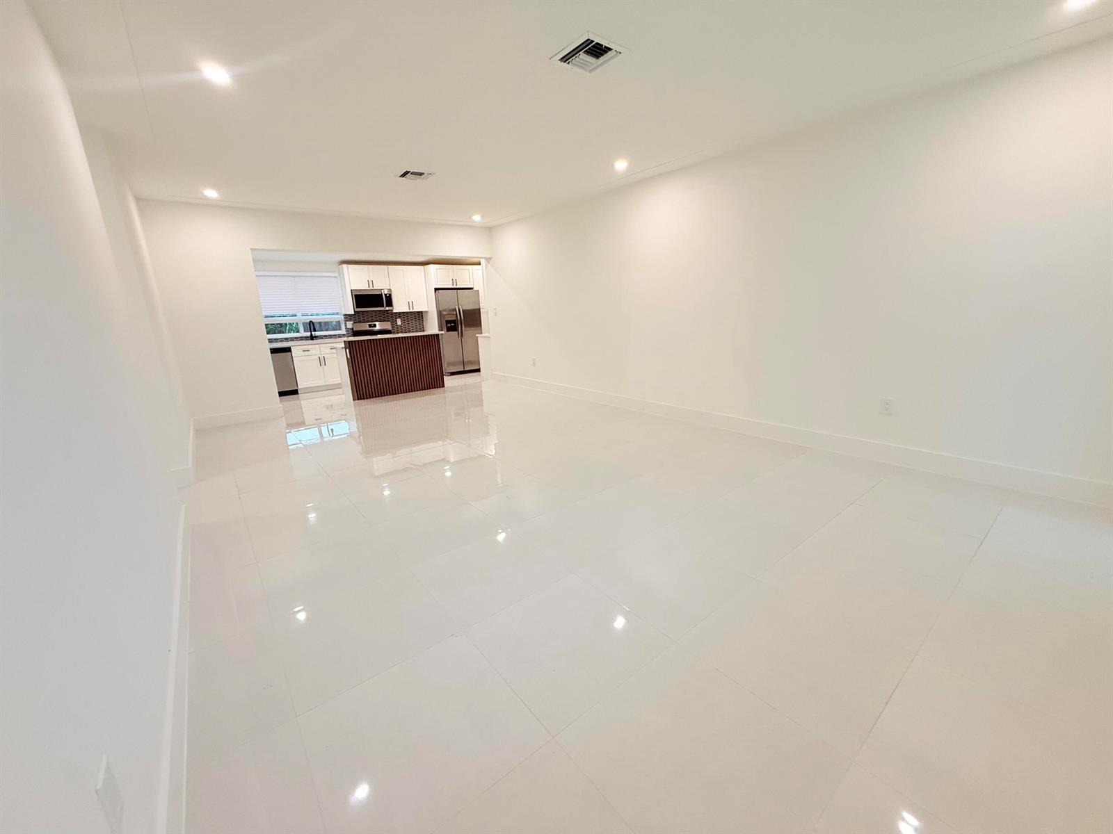 An open-concept living area with white tile floors leads to a modern kitchen — 345 Pinehurst Road, Palm Springs FL 33461, PALM SPRINGS, FL