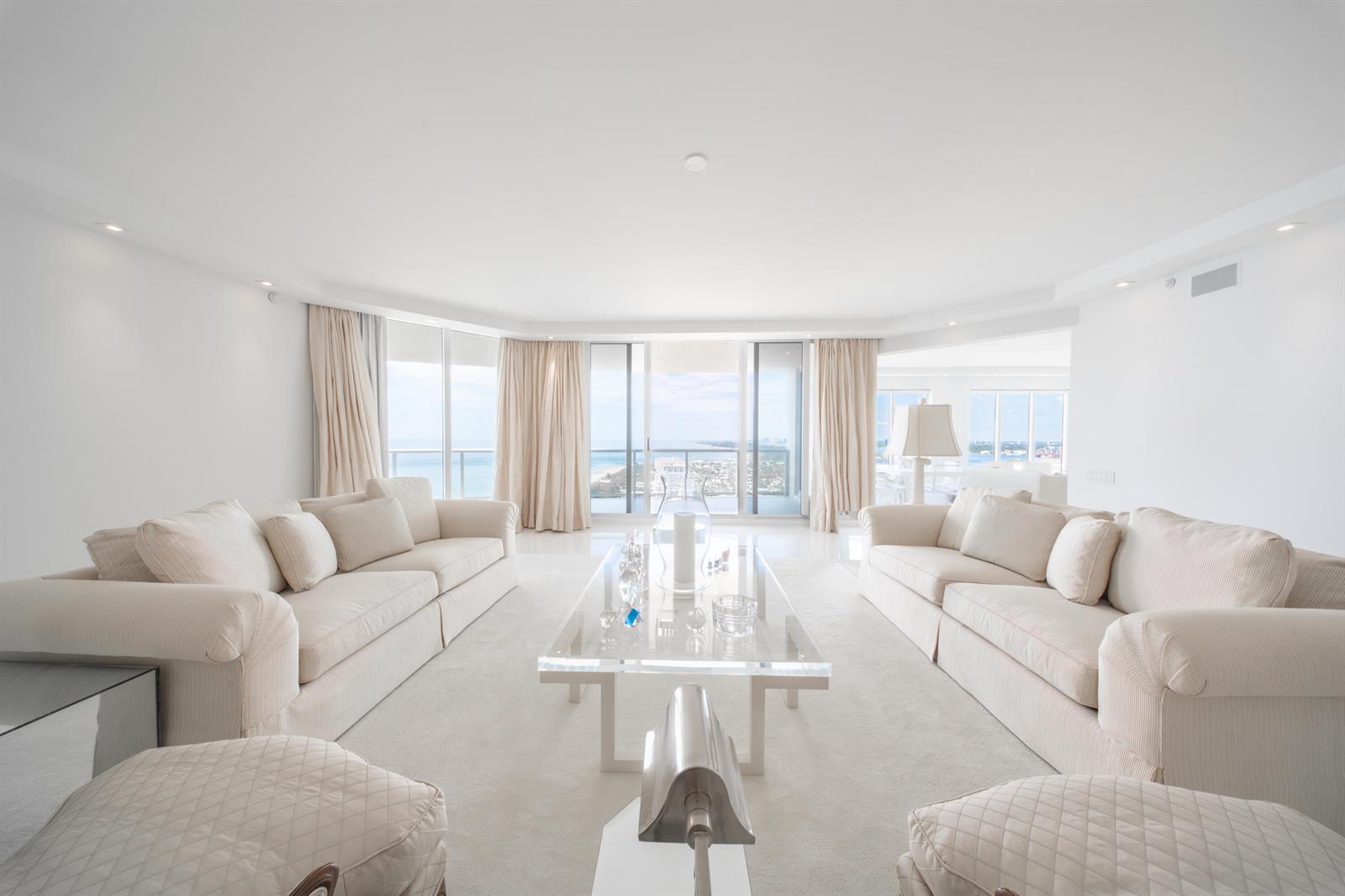 A bright living room features two beige sofas, a glass coffee table, and ocean views — 2700 N Ocean Drive # 2503a, Riviera Beach FL 33404, RIVIERA BEACH, FL