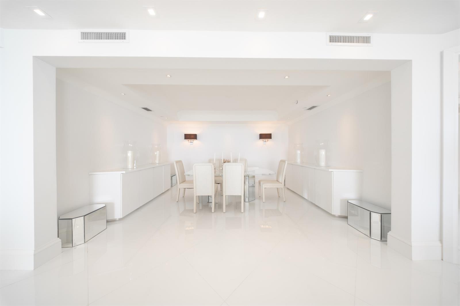 A bright, minimalist dining room features white walls, glossy tile floors, and a glass table — 2700 N Ocean Drive # 2503a, Riviera Beach FL 33404, RIVIERA BEACH, FL