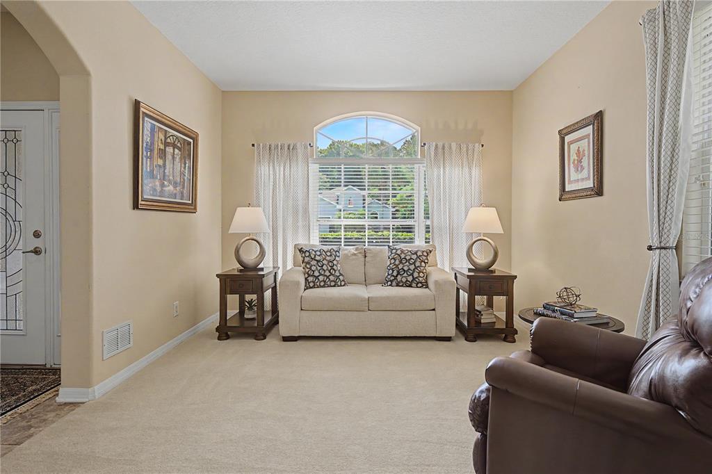 A living room features a beige loveseat, two end tables with lamps, and a large window — 8711 PRESTON WOODS COURT, LAND O LAKES, FL