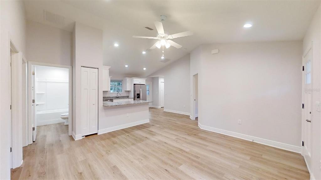 An open-concept living area with light wood flooring, a ceiling fan, and a kitchen island — 24294 NW TAMARIND LANE, DUNNELLON, FL