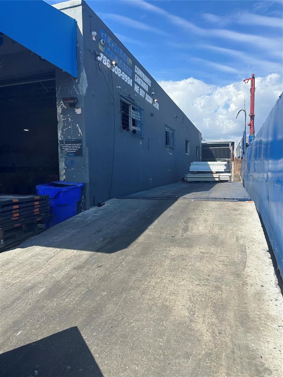 An exterior view of a gray industrial building with a concrete driveway and scrap metal — 2717 NW 34th Street, Miami FL 33142, MIAMI, FL