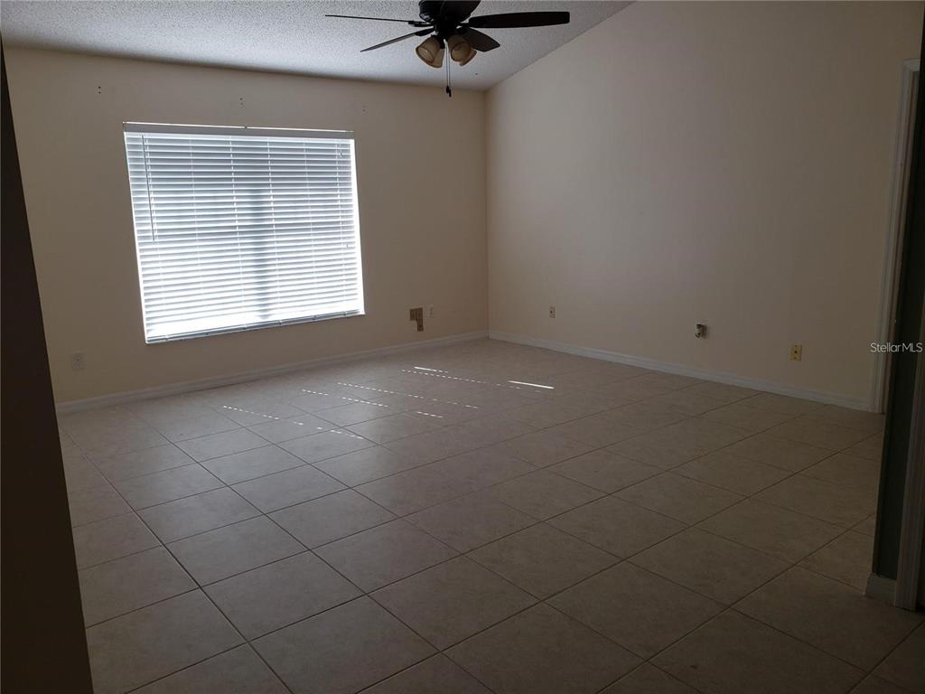 An empty room with beige tile flooring, a large window with blinds, and a ceiling fan — 3792 DUNWICH AVENUE, ORLANDO, FL