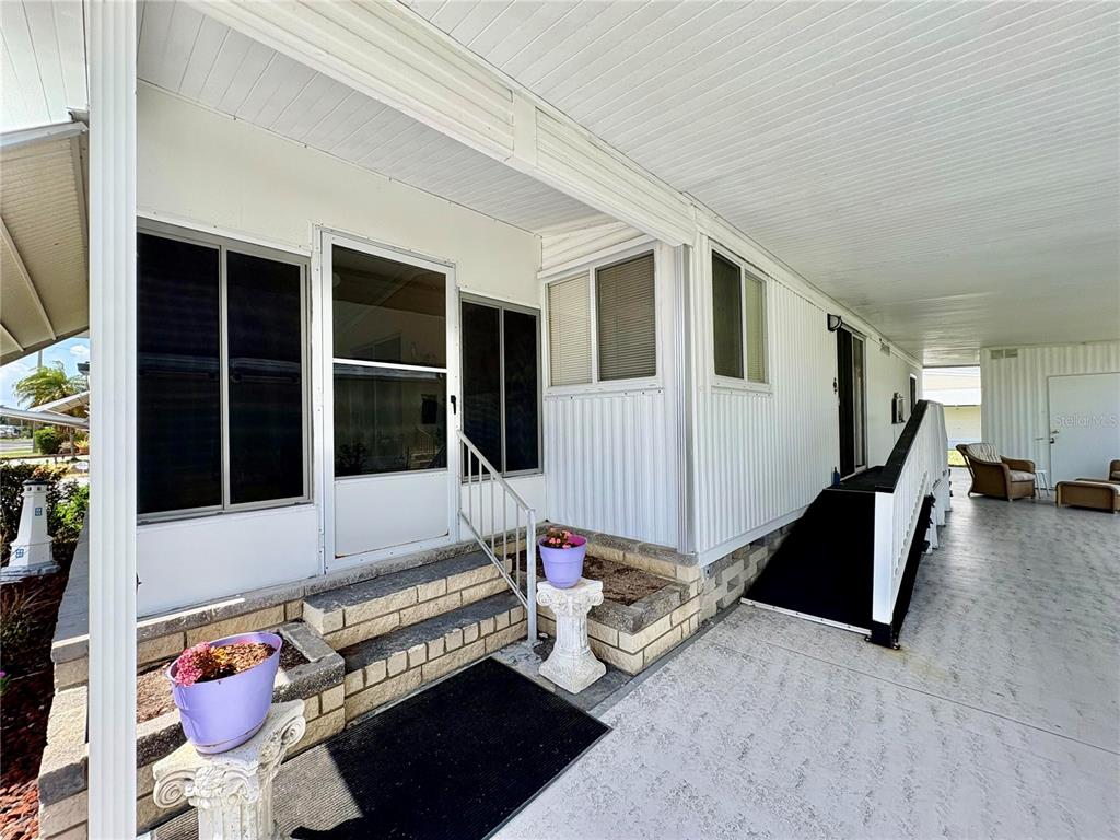 The exterior of a mobile home features a covered carport, stairs, and a screened entrance — 3049 LONGVIEW LANE, NORTH FORT MYERS, FL