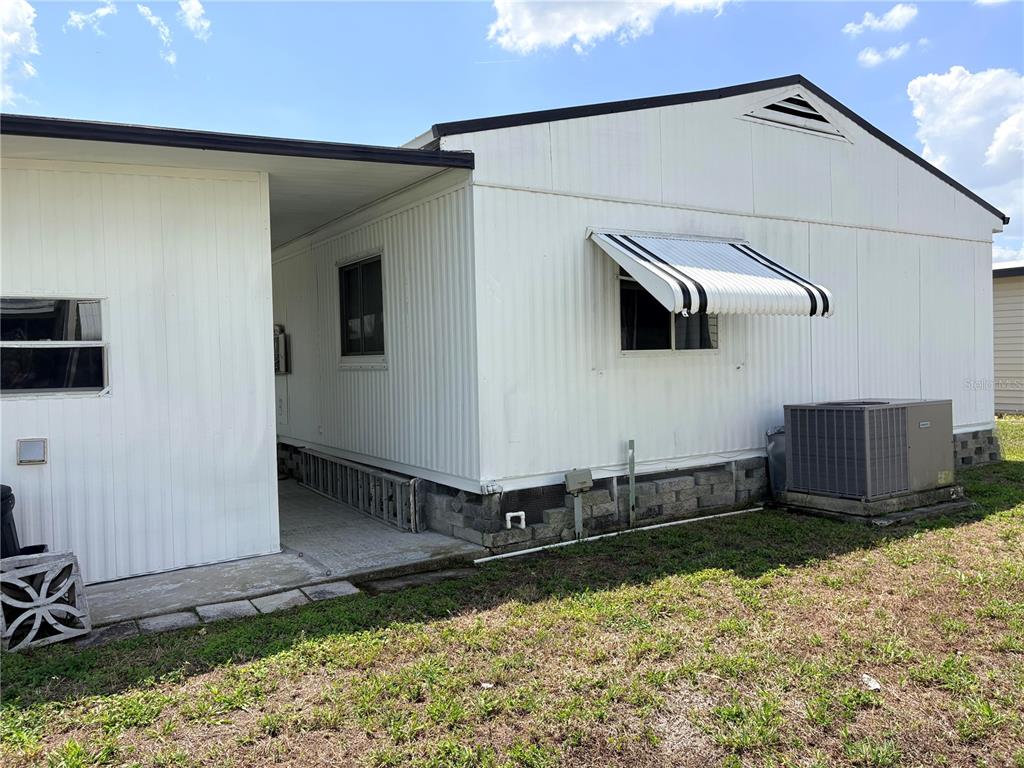 The exterior of a white mobile home features a metal awning and an air conditioning unit — 3049 LONGVIEW LANE, NORTH FORT MYERS, FL
