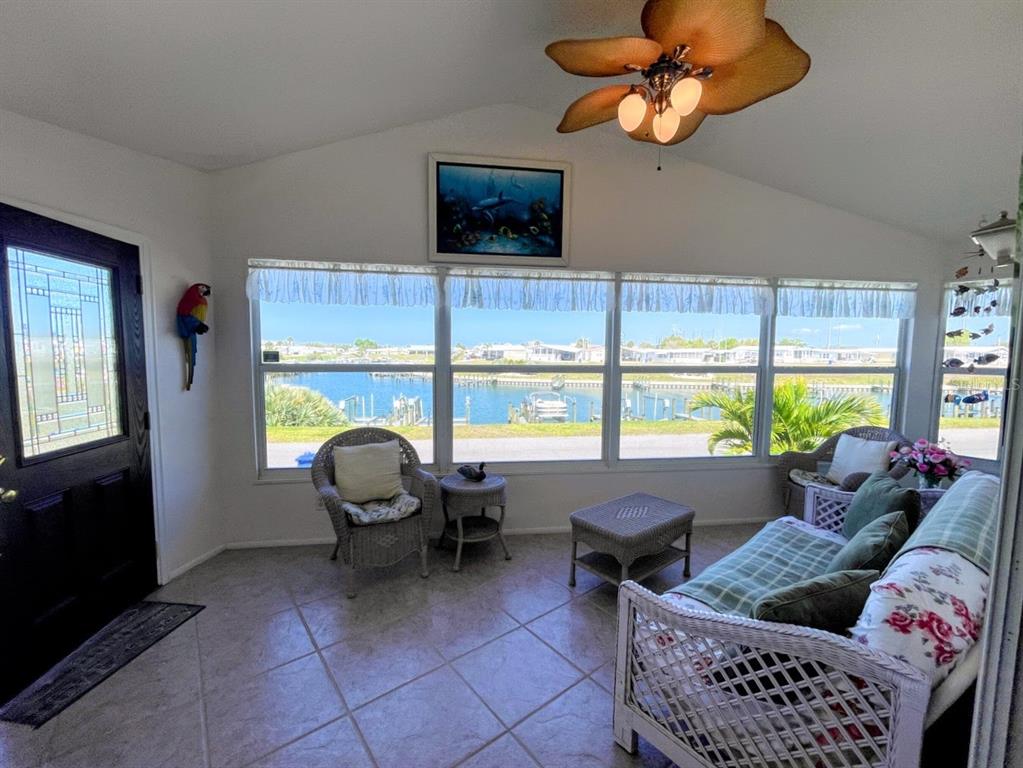 A sunroom with tile floors, wicker furniture, and large windows overlooking a canal and boats — 817 S WATERWAY, VENICE, FL