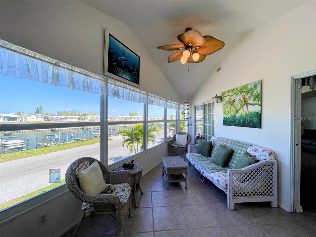 A sunroom with tile floors, wicker furniture, and large windows overlooking a canal and boats — 817 S WATERWAY, VENICE, FL