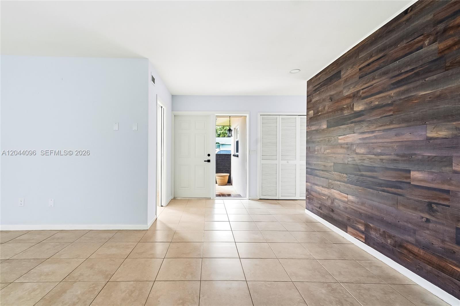 An entryway features tile flooring, a wood-paneled accent wall, and a white front door — 106 E Park Ln E, Hypoluxo FL 33462, HYPOLUXO, FL