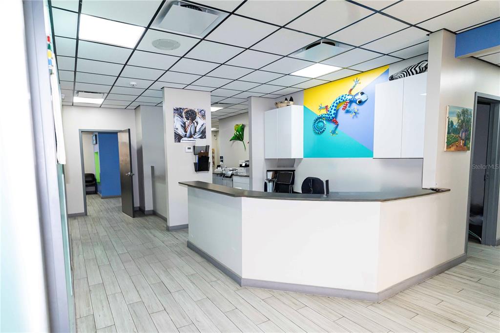 A reception area features a white desk, a colorful lizard wall art, and drop ceilings — 4804 EDGEWATER DRIVE, ORLANDO, FL