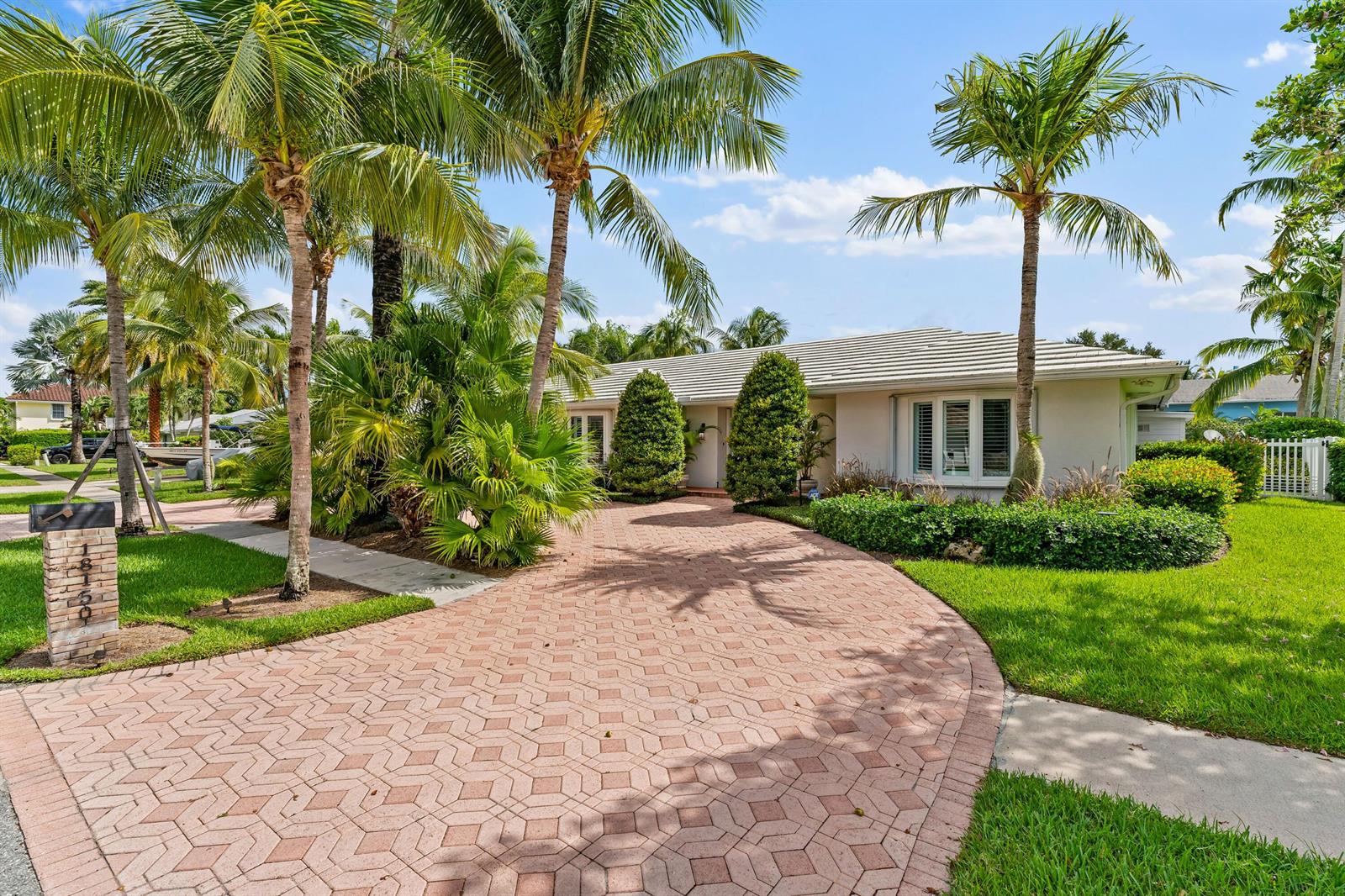 A single-story house with a paved driveway, palm trees, and a manicured lawn — 18150 Perigon Way, Jupiter FL 33458, JUPITER, FL