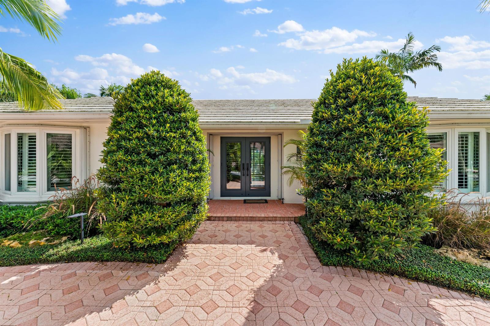A paved walkway leads to the double front doors of a house flanked by large shrubs — 18150 Perigon Way, Jupiter FL 33458, JUPITER, FL