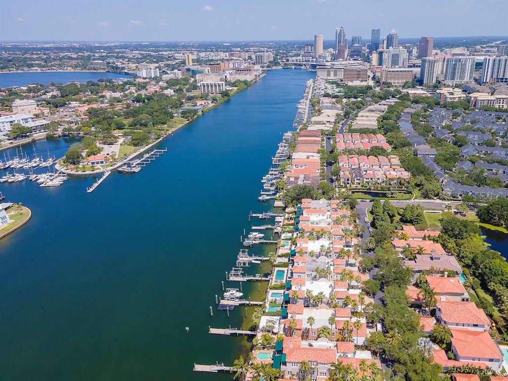 An aerial view of a waterfront residential neighborhood with private boat docks and city skyline — 1109 ABBEYS WAY, TAMPA, FL