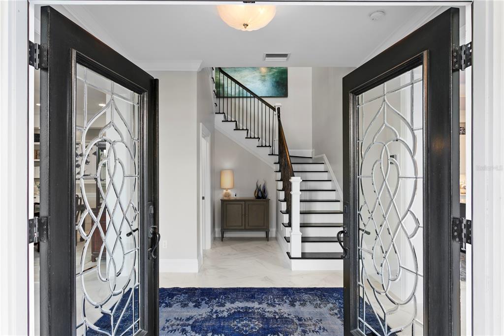 An entryway features double glass-paneled doors, a staircase with black treads, and a blue rug — 1109 ABBEYS WAY, TAMPA, FL