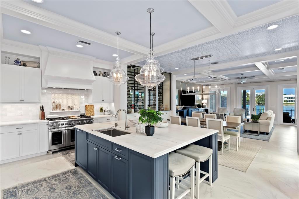 A kitchen with a blue island, white cabinets, and a dining area overlooking the water — 1109 ABBEYS WAY, TAMPA, FL