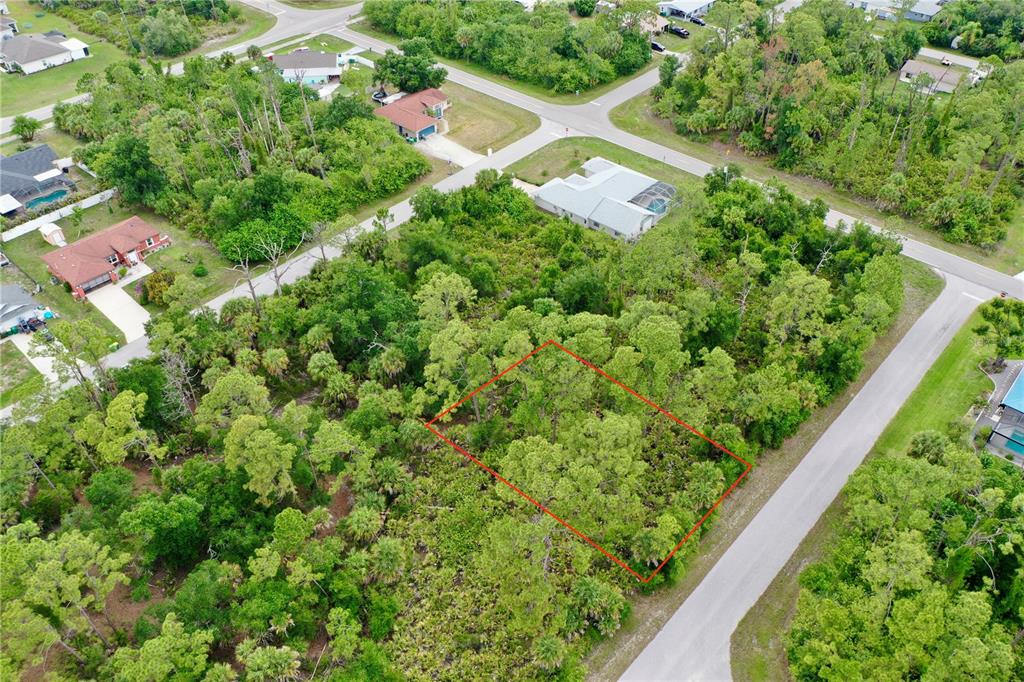 An aerial view shows a rectangular, wooded vacant lot outlined in red near residential streets — 3027 SUDBURY STREET, PORT CHARLOTTE, FL