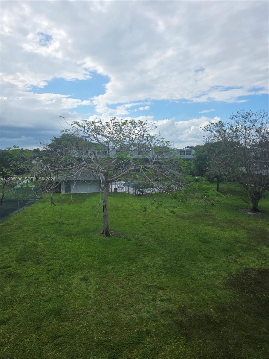 A grassy yard with trees and a fenced swimming pool under a cloudy sky — 9500 SW 3rd St # 259, Boca Raton FL 33428, BOCA RATON, FL