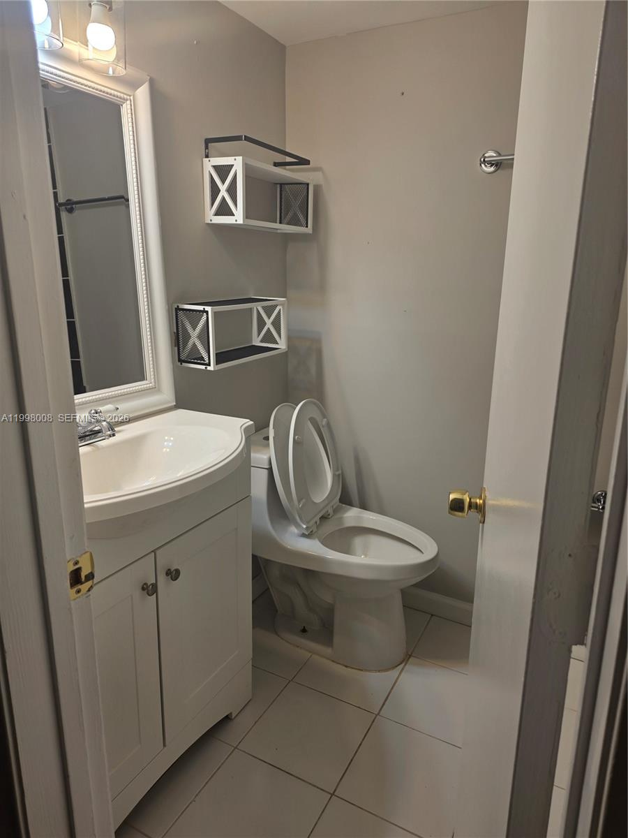 A small bathroom features a white vanity, a toilet, and two wall-mounted shelves — 9500 SW 3rd St # 259, Boca Raton FL 33428, BOCA RATON, FL