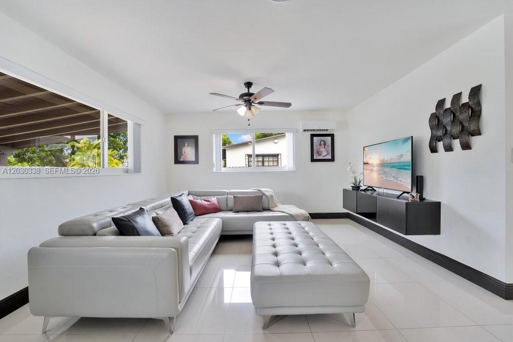 A living room features a white sectional sofa, a matching ottoman, and a wall-mounted television — 8625 SW 44th St, Miami FL 33155, MIAMI, FL