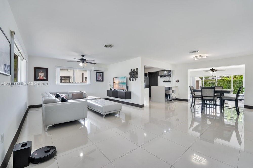 A bright, open-concept living and dining area features white tile floors and modern furnishings — 8625 SW 44th St, Miami FL 33155, MIAMI, FL