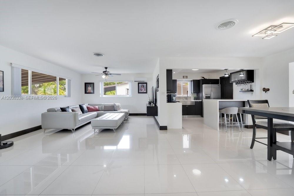 A bright, open-concept living room and kitchen feature white tile floors and modern furnishings — 8625 SW 44th St, Miami FL 33155, MIAMI, FL