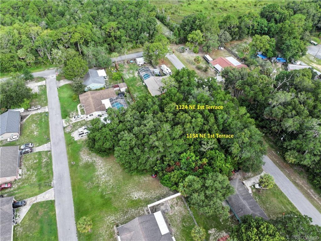 An aerial view shows two adjacent wooded lots situated between residential streets and houses — 1124 NE 1ST TERRACE, CRYSTAL RIVER, FL