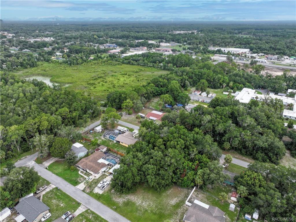 An aerial view shows several residential houses surrounded by dense trees and a large field — 1124 NE 1ST TERRACE, CRYSTAL RIVER, FL