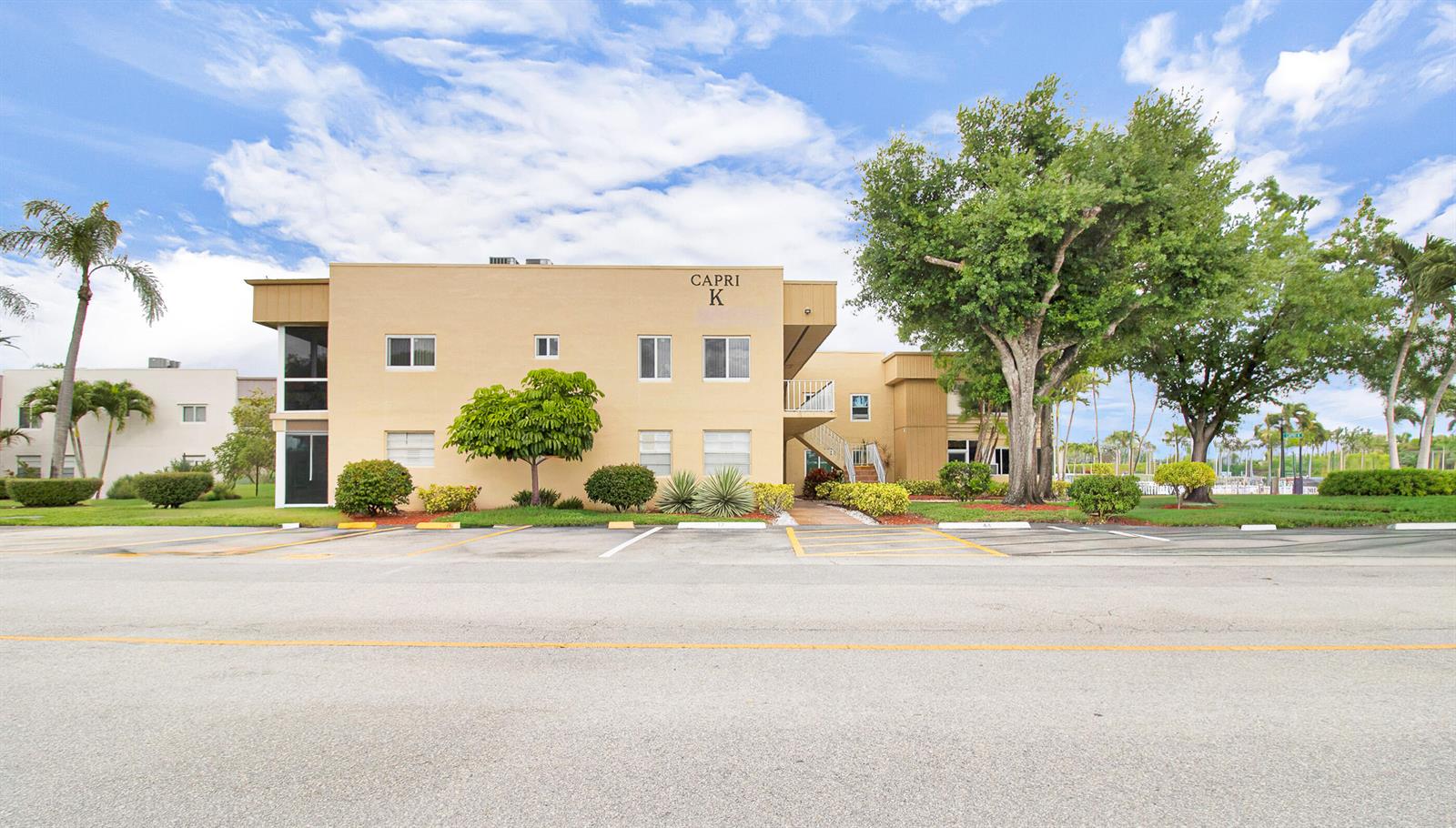 A two-story tan apartment building labeled Capri K stands behind a parking lot — 525 Capri K, Delray Beach FL 33484, DELRAY BEACH, FL