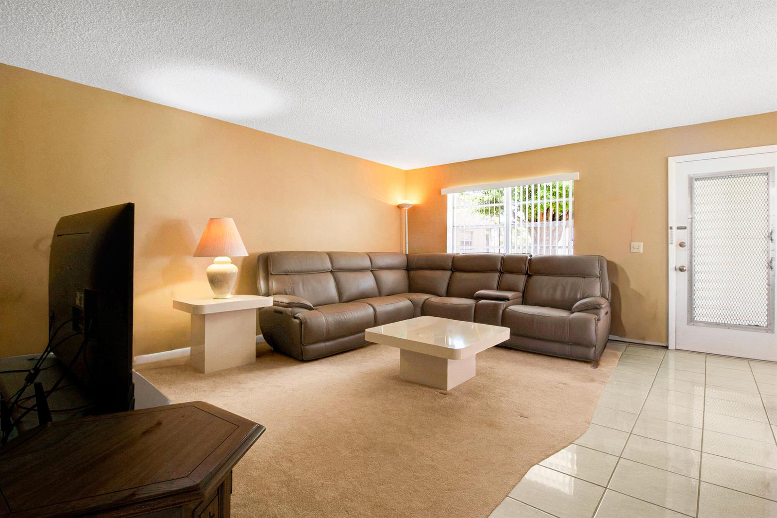 A living room features a brown sectional sofa, a coffee table, and a beige carpet — 525 Capri K, Delray Beach FL 33484, DELRAY BEACH, FL