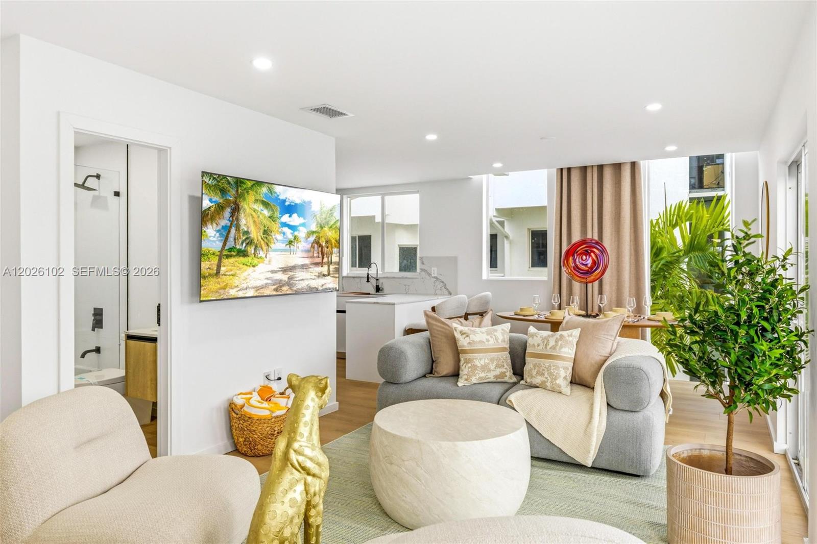 A modern living room features a gray sofa, round coffee table, and an open kitchen — 1975 Calais Dr # 5, Miami Beach FL 33141, MIAMI BEACH, FL